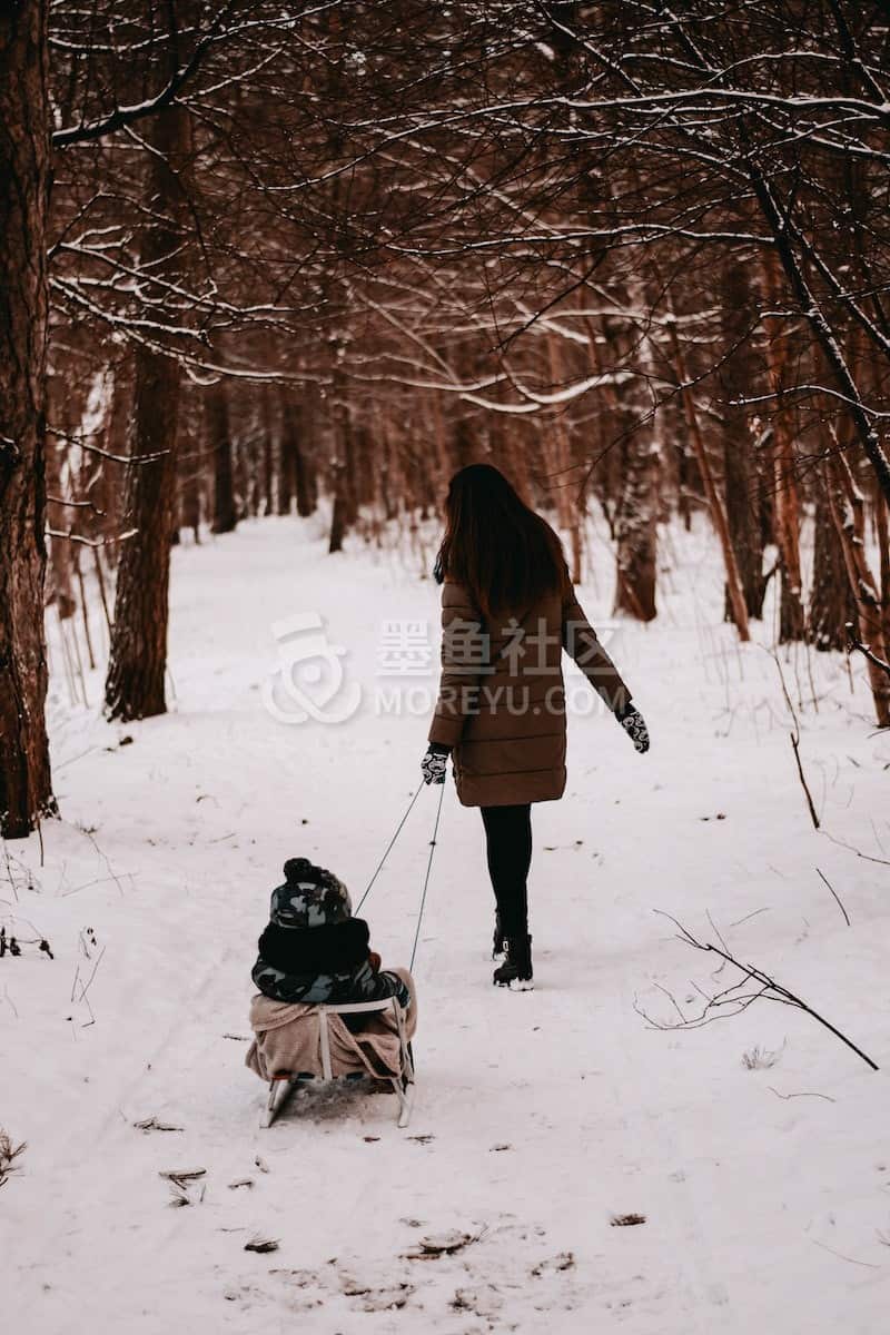 woman dragging sled with baby riding on it