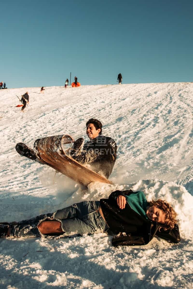 man in black jacket lying on snow covered ground during daytime